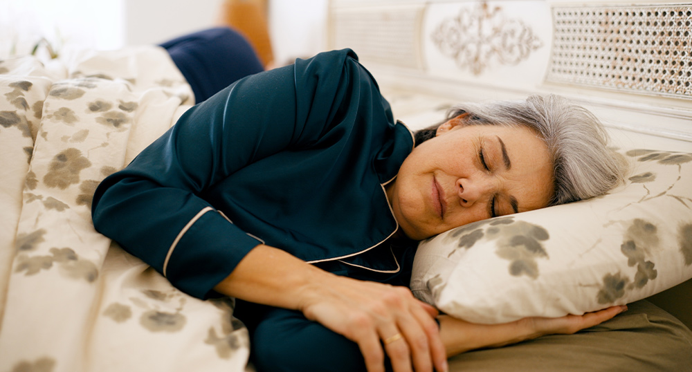 Middle-aged woman sleeping soundly in bed, illustrating the gut-brain axis and sleep